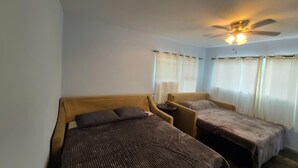 A room with two beds, a ceiling fan, and curtains. - Spacious North Shore cottage with lush mountain scenery in the country! (Waialua)