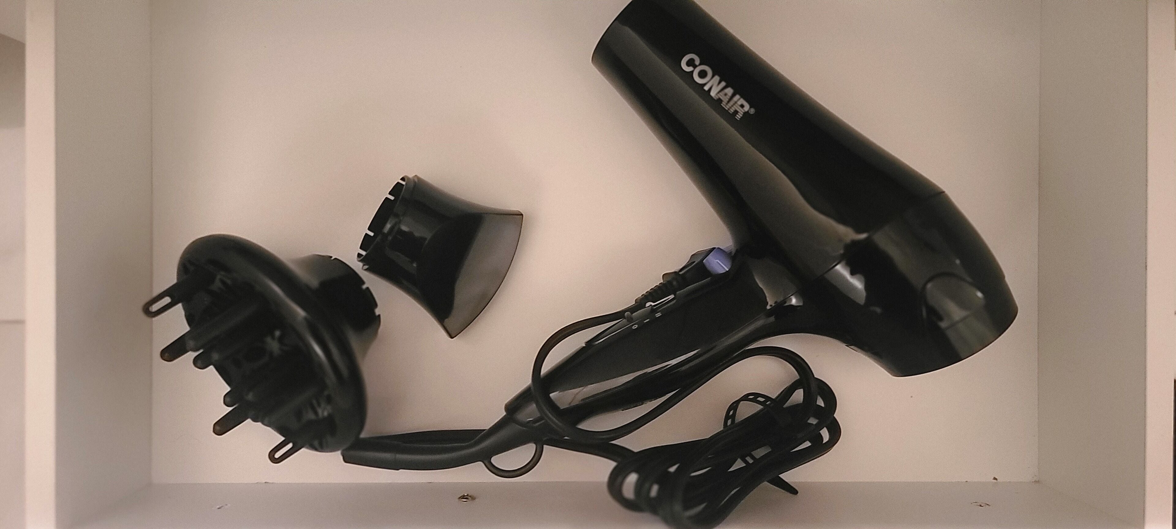 Une boîte contenant un sèche-cheveux, son câble d’alimentation et un adaptateur de prise.