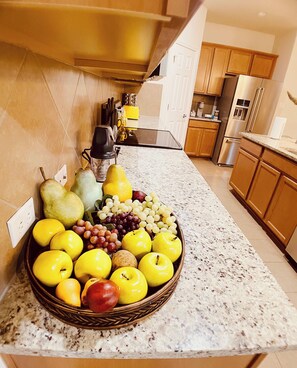 Una cocina con encimera de granito, armarios de madera y electrodomésticos de acero inoxidable.