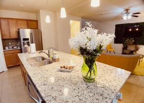 A modern kitchen with granite countertops, stainless steel appliances, and a central island with a vase of white flowers.
