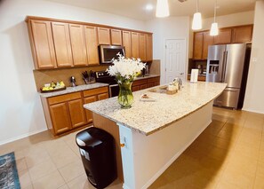 A modern kitchen with wooden cabinets, stainless steel appliances, and a granite countertop.