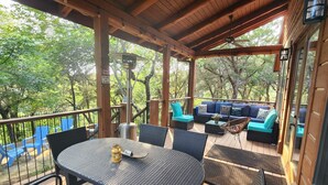 Un área de estar techada al aire libre con una mesa y sillas, rodeada de sillas azules y un sofá con cojines color turquesa.