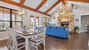 Un salón amplio con chimenea de piedra, un sofá azul y una mesa de comedor con sillas.