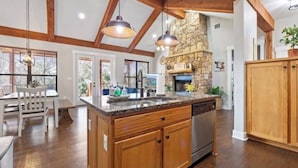 Una cocina amplia con una isla grande, armarios de madera y una chimenea de piedra.