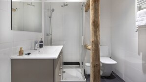 A modern bathroom with a glass-enclosed shower, a white sink with a mirror, and a toilet.