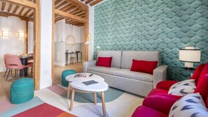 A modern living room with a sofa, ottomans, and a coffee table. There is a dining area with chairs and a table.