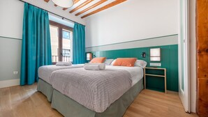 A modern bedroom with a large bed, teal curtains, and a wooden ceiling.