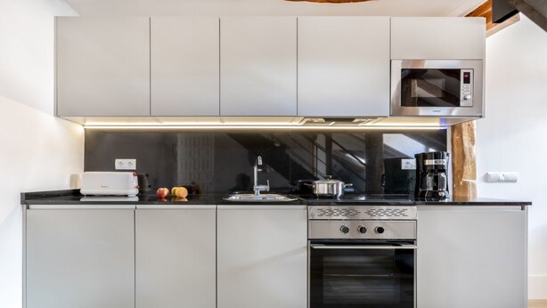Una cocina moderna con microondas, horno y cafetera integrados.