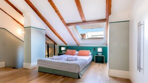 Un dormitorio con tragaluz, vigas de madera, una cama con almohadas, una mesita de noche y un armario empotrado.