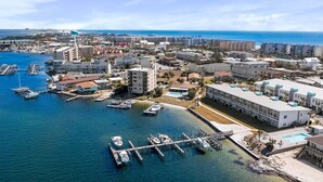 Vista aérea de un pueblo costero con un puerto deportivo, edificios y una playa.