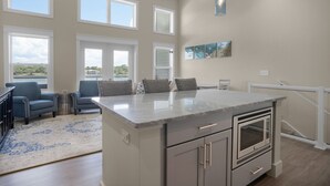 Una cocina amplia con una isla grande, varios ventanales y un ventilador de techo.