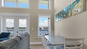 Una habitación con vistas a un lago, una mesa de comedor con sillas, un sofá y una pared decorada con obras de arte.