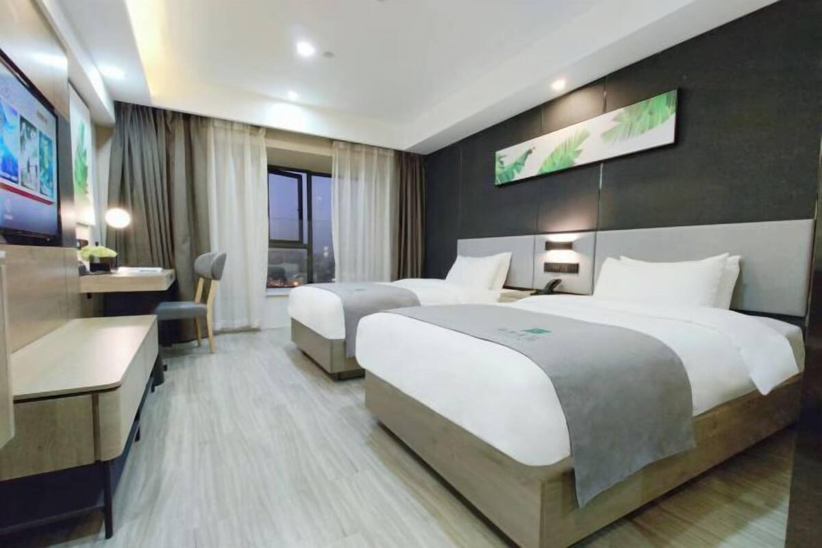 Une chambre d’hôtel moderne équipée de deux lits, d’un bureau et d’une télévision.
