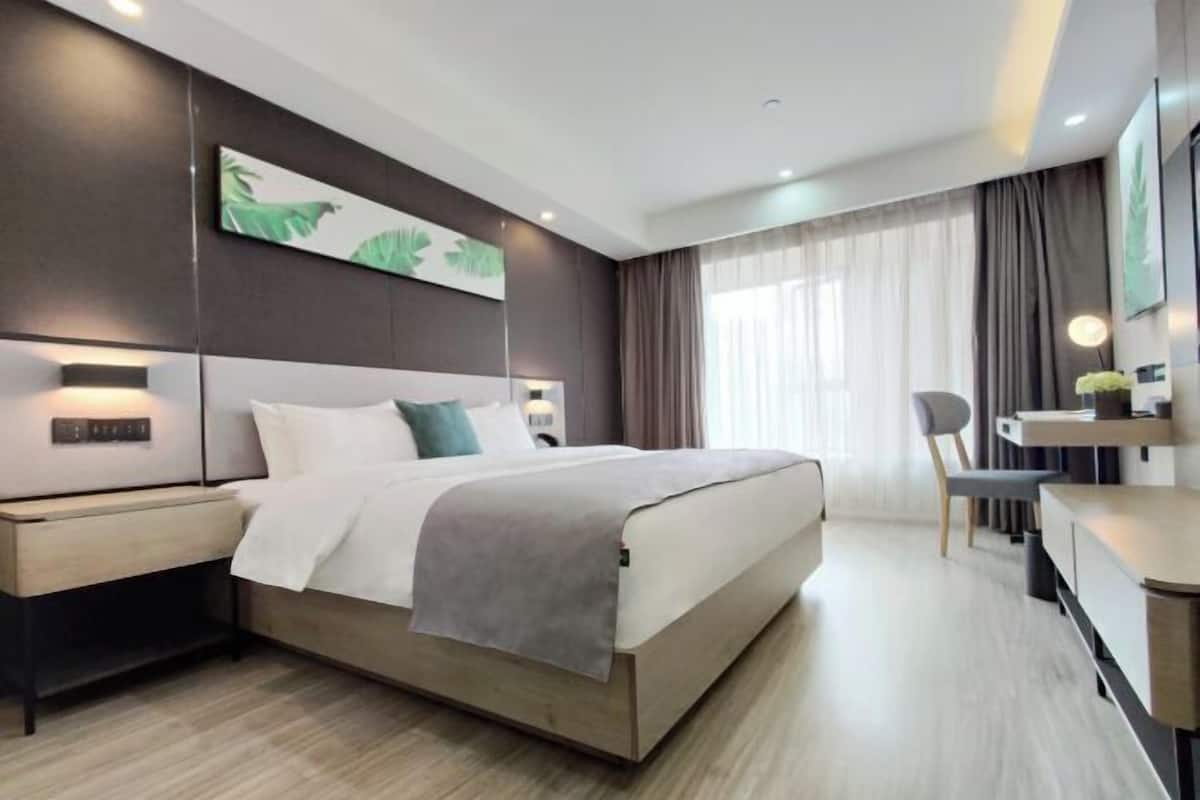 Une chambre d’hôtel moderne, dotée d’un grand lit, de tables de chevet, d’un bureau et d’une chaise.