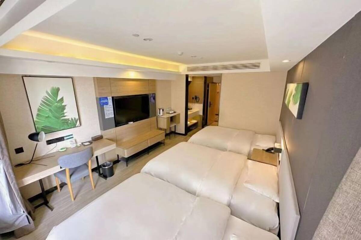 Une chambre d’hôtel moderne dotée d’un grand lit, d’un bureau avec un ordinateur, d’une télévision à écran plat et d’un coin salon.