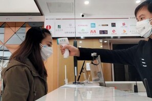 A person using a handheld device, likely for temperature measurement, in a room with a visible logo on the wall. - Shankee Tea Style Hotel (Kunming South High-Speed Railway Station Chunrong Street Subway Station) (Kunming)