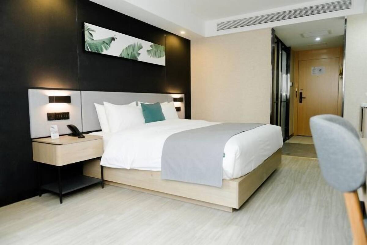 Une chambre d’hôtel moderne, dotée d’un grand lit, de tables de chevet, d’un bureau et d’une chaise.