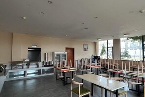 A spacious restaurant with high tables and chairs, a refrigerator, and a trash bin. - Shankee Tea Style Hotel (Kunming South High-Speed Railway Station Chunrong Street Subway Station) (Kunming)
