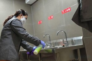 A person cleaning a sink in a restroom with a sign indicating a three-star rating. - Shankee Tea Style Hotel (Kunming South High-Speed Railway Station Chunrong Street Subway Station) (Kunming)