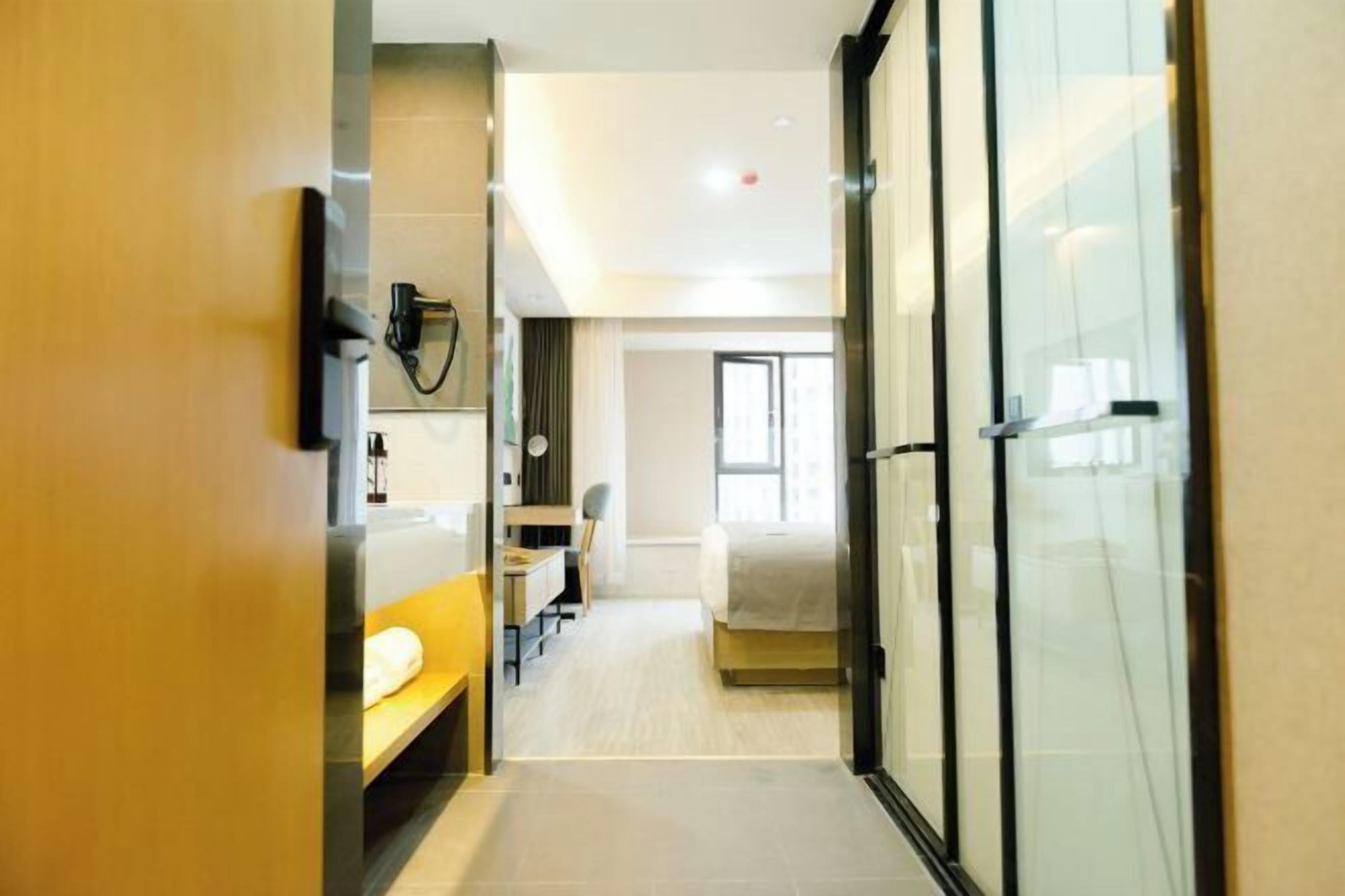 Une chambre d’hôtel moderne équipée d’un lit, d’un bureau, d’une chaise et d’une cloison en verre.