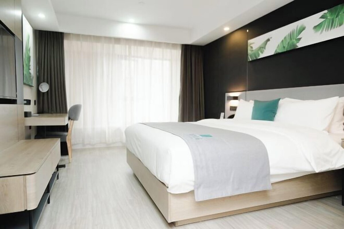 Moderni hotellihuone, jossa on suuri sänky, työpöytä ja tuoli.