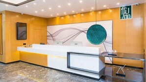 A reception area with a marble floor, a reception desk, a wall-mounted artwork, and a sign with Chinese characters. - Shankee Tea Style Hotel (Kunming South High-Speed Railway Station Chunrong Street Subway Station) (Kunming)