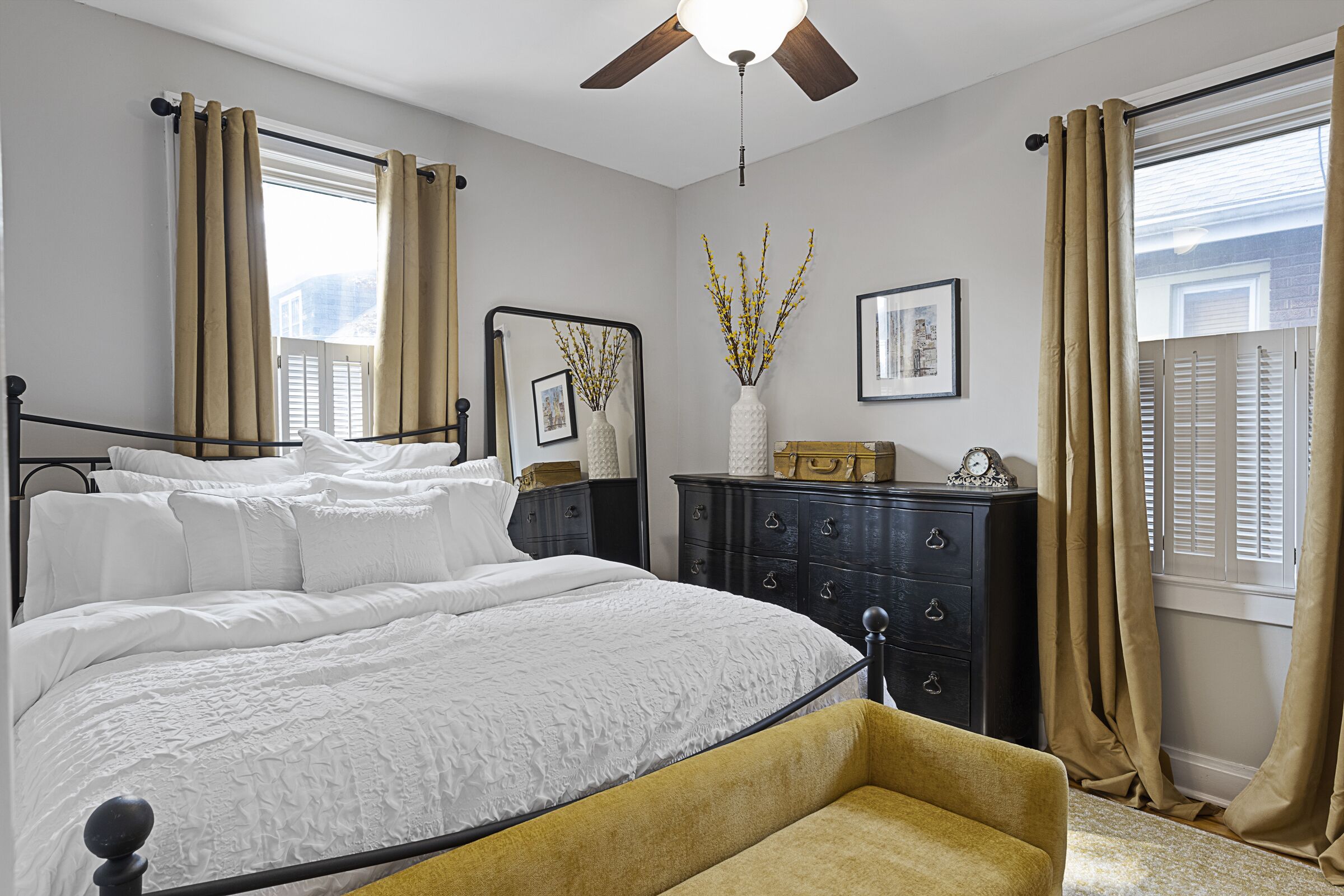 A bedroom with a bed, a dresser, a mirror, and a window with curtains.