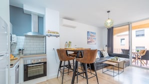 A modern kitchen with a built-in oven, a dining area with two chairs, a sofa, and a table. - Apartment in the center completely renovated (Empuriabrava)