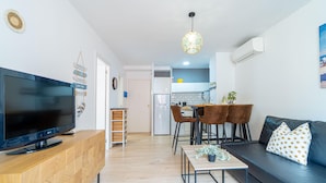A modern living room with a flat-screen TV, wooden entertainment unit, and a black leather sofa. - Apartment in the center completely renovated (Empuriabrava)