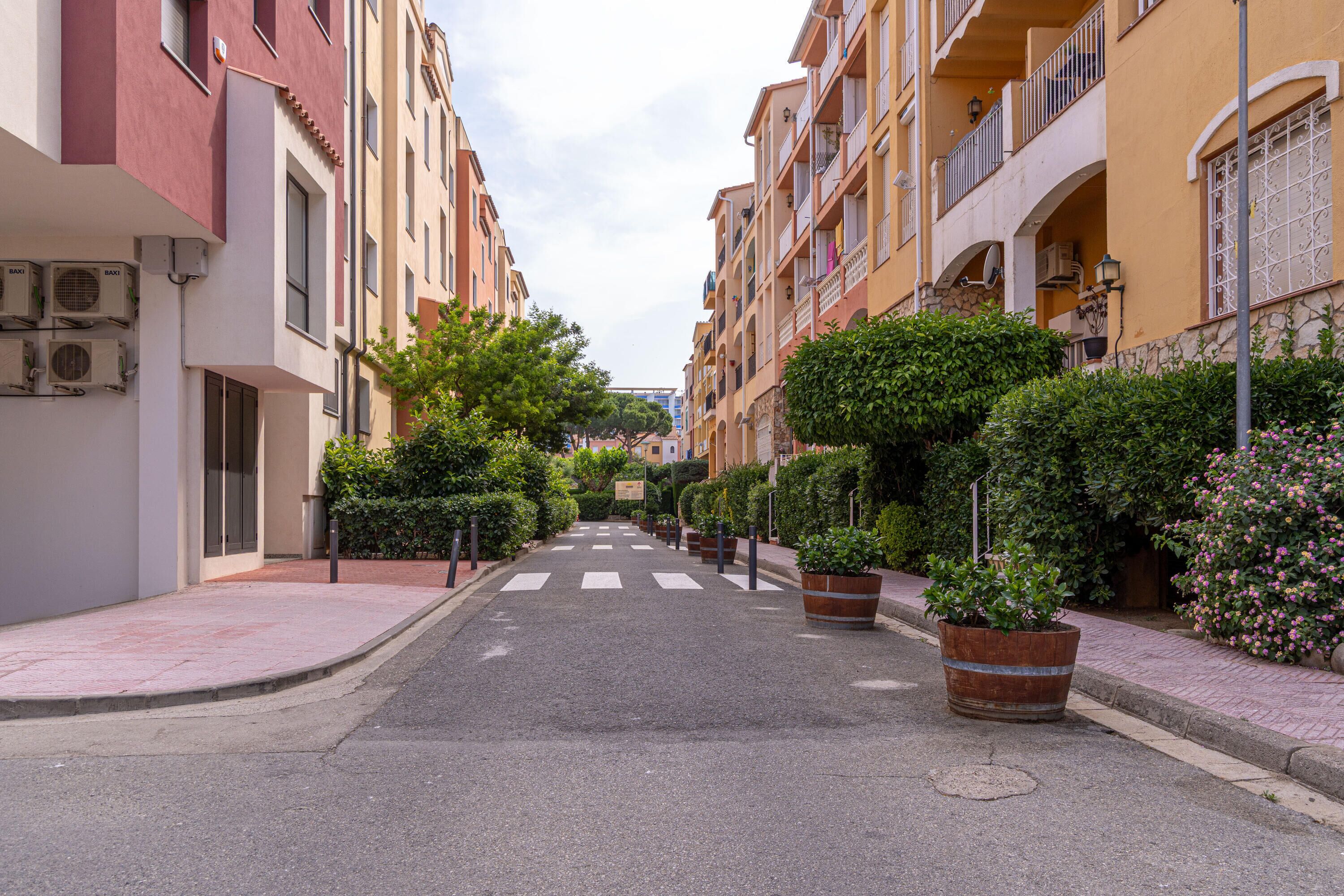 Eine enge Straße, gesäumt von mehrstöckigen Gebäuden, jedes mit Balkonen und Klimaanlagen.