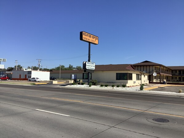 A motel with a sign for 'Silver Spur Vintage Inn Suites' and a welcome sign indicating extended stay rates. - Silver Spur Vintage Inn & Suites (Dodge City)