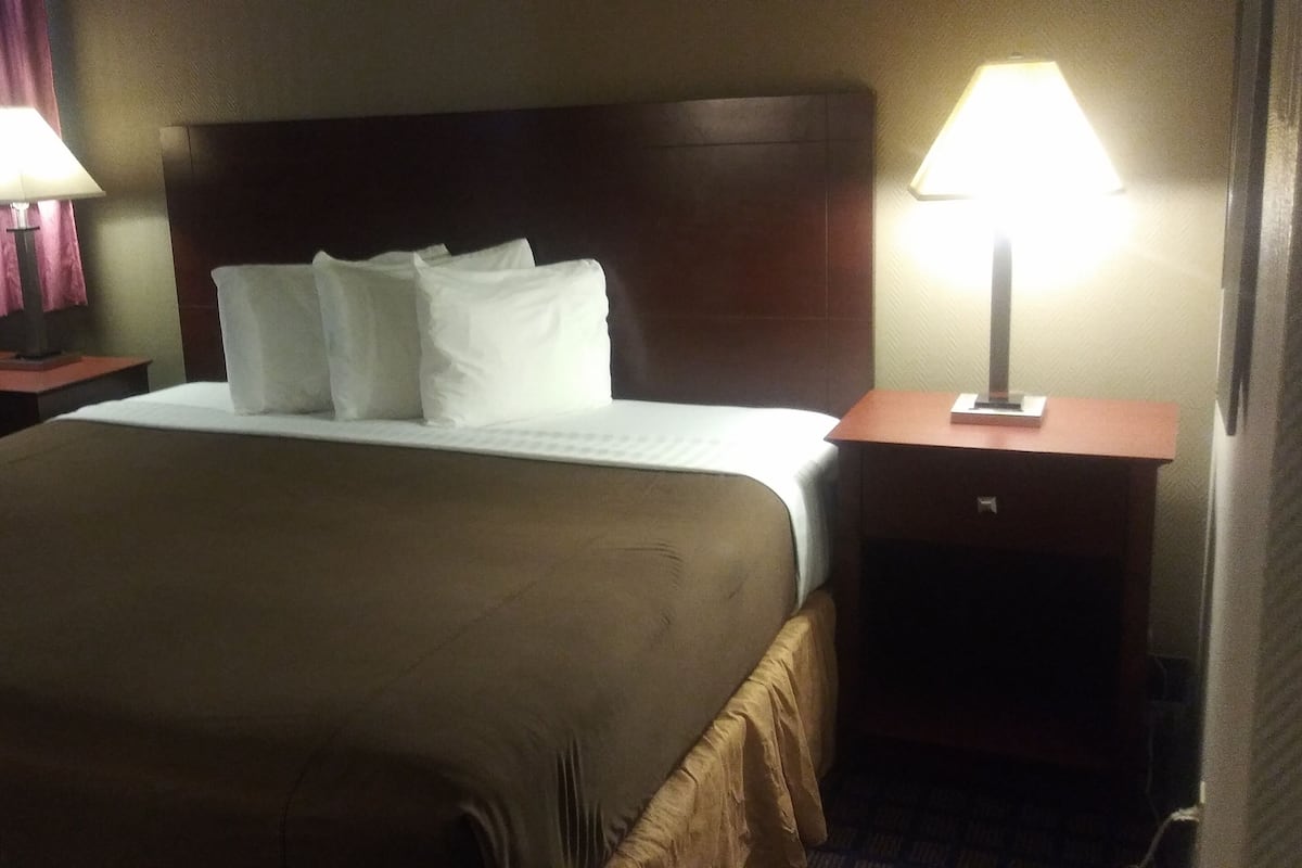 A hotel room with a large bed, two bedside tables with lamps, and a window with curtains.