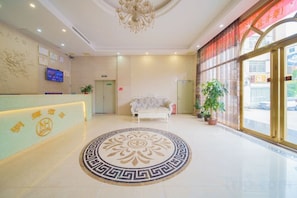 A hotel lobby with a reception desk, a sofa, a chandelier, and a large window. - Minghui Hotel (Haifeng)