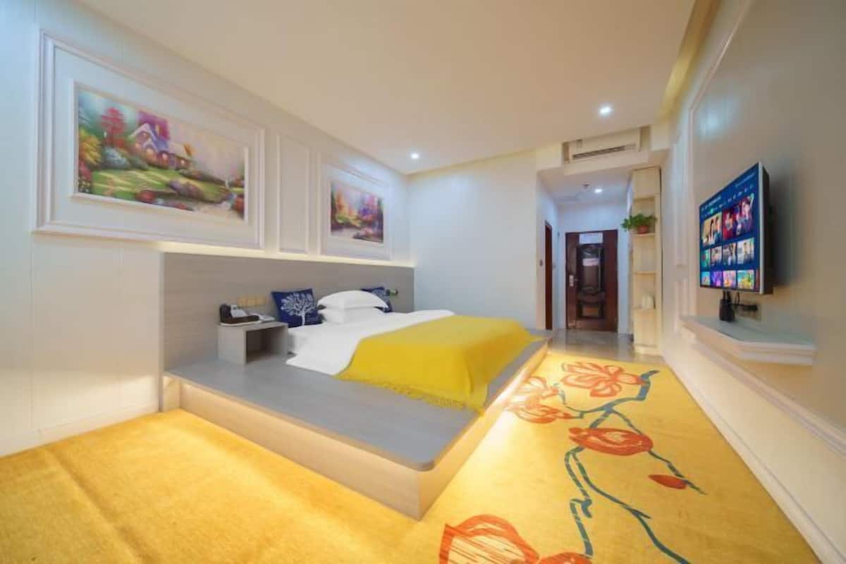A bedroom with a bed, bedside table, and a TV on the wall.
