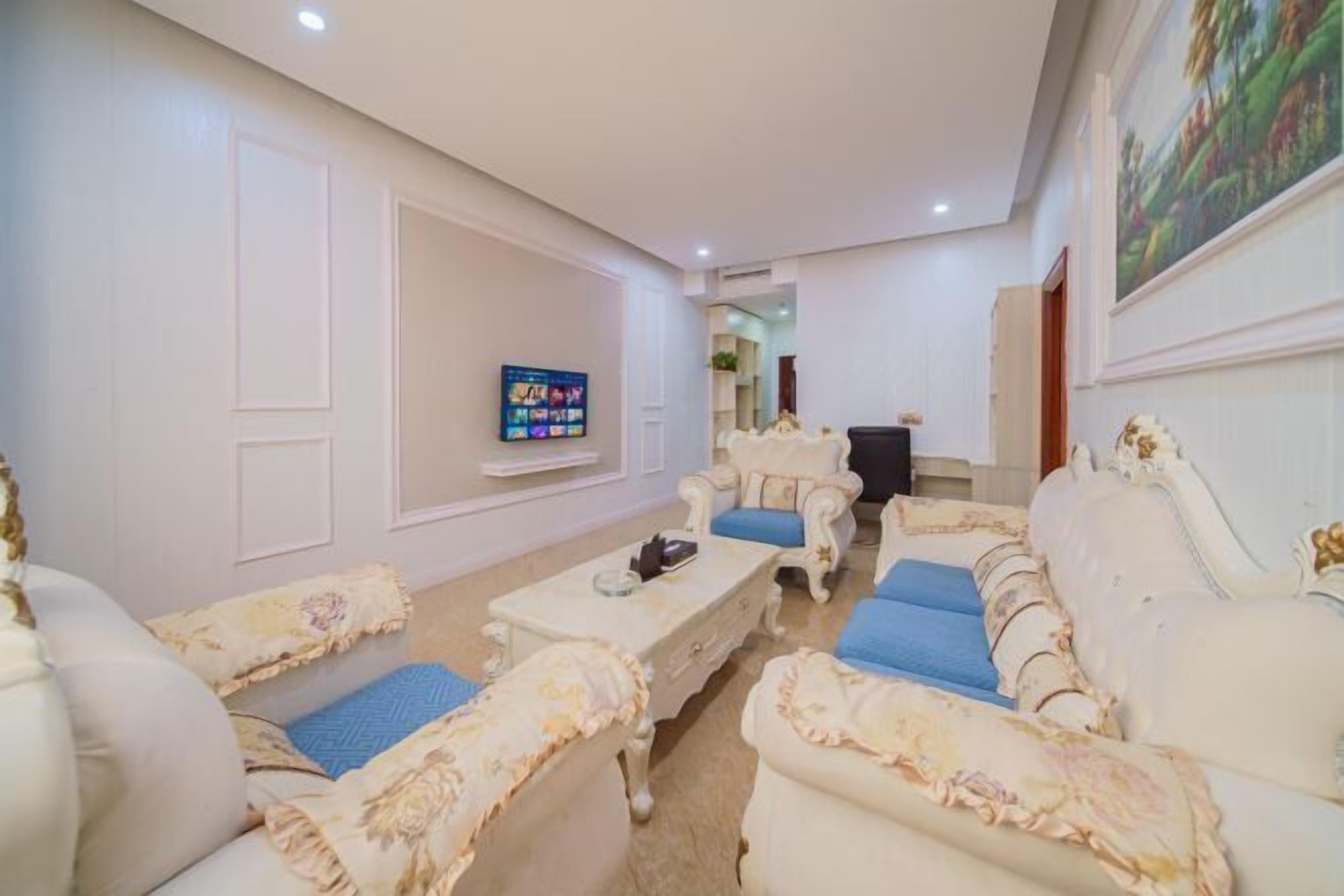 A living room with a sofa set, a coffee table, and a television mounted on the wall.