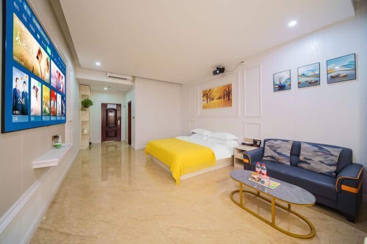 A hotel room with a bed, a sofa, a coffee table, and wall art.