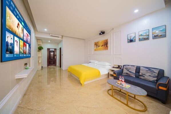 A hotel room with a bed, a sofa, a coffee table, and wall art.