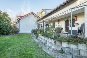 Ein Wohngebäude mit Garten, Sitzgelegenheiten im Freien und einer Pergola.