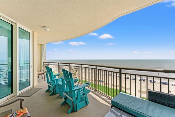 Un balcon avec des chaises, une vue sur la plage et une balustrade.
