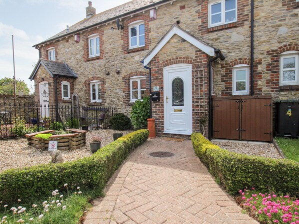 A stone house with a paved driveway, a white door, and a mailbox. - Knapp Cottage (Weymouth)