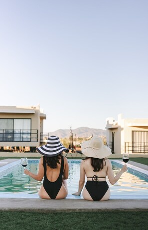 Dos mujeres sentadas junto a una piscina con vistas a la montaña.