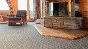 A cozy living room with a stone fireplace, wooden ceiling, and a comfortable chair. - Ahmic Lake Resort's 3-Bedroom Cottage (Red Fox Cottage) (Magnetawan)