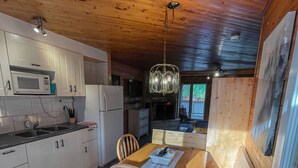 Una cocina con armarios de madera, microondas y una mesa de comedor con sillas.