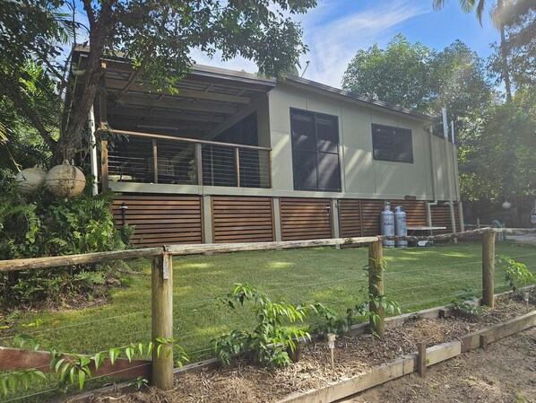 A single-story RV with a large window and a covered porch area.