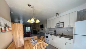 Una cocina moderna con armarios blancos, microondas integrado, estufa y una amplia mesa de comedor de madera con sillas.