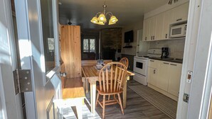 Una cocina y comedor integrados con una mesa de madera, sillas y una araña.