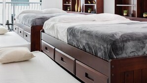 A modern bedroom with two beds, built-in shelving, and a large window. - Lovely Brickell Oceanview Studio (Miami)