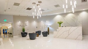 A modern reception area with a marble reception desk, black leather chairs, and a sign reading "The Club at Brickell Bay Condominium". - Lovely Brickell Oceanview Studio (Miami)