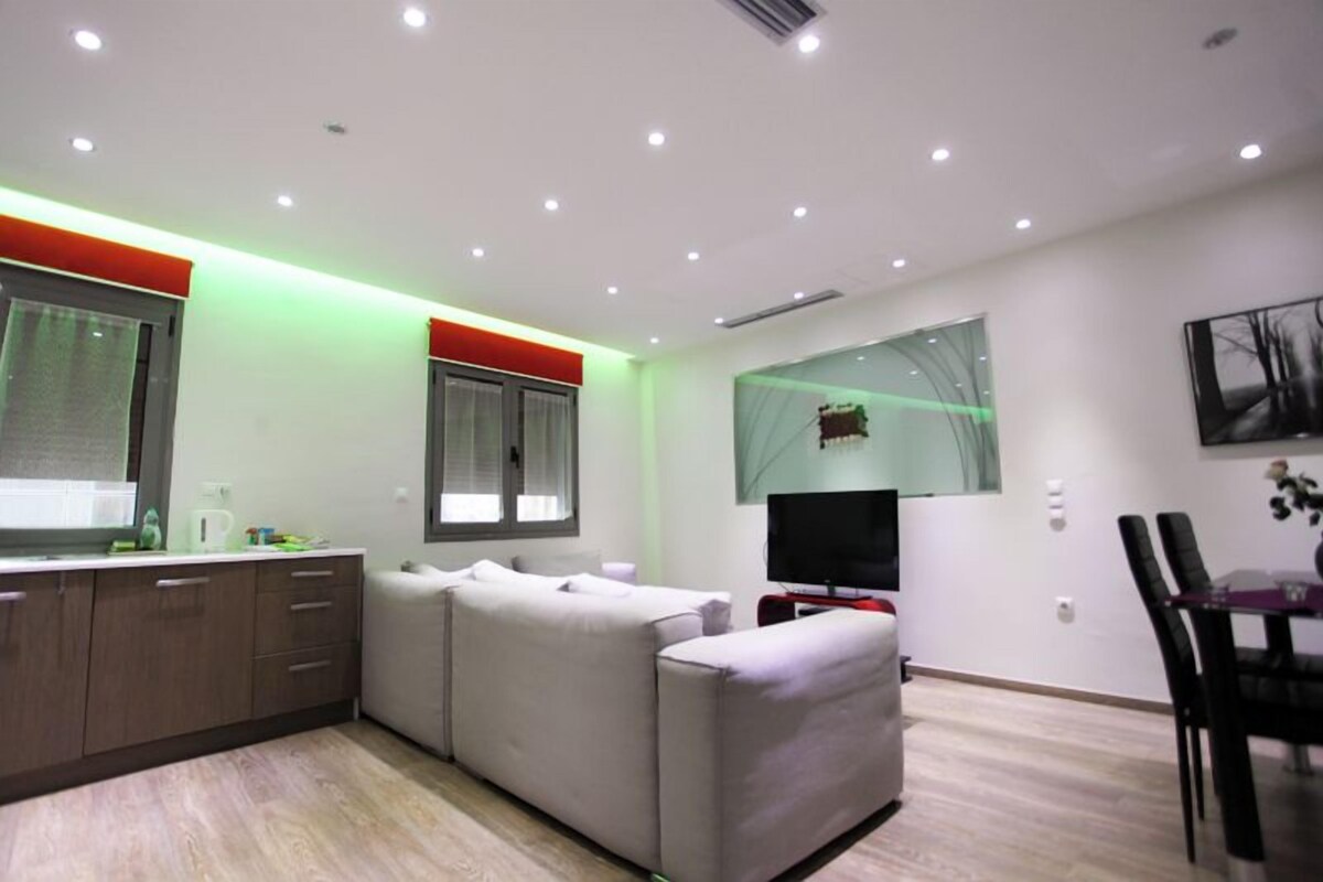 Una sala de estar moderna con un sofá, un televisor y un comedor con sillas.