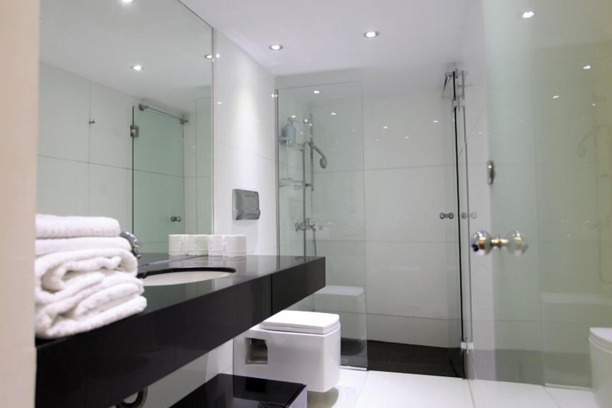 A modern bathroom with a glass-enclosed shower, a black vanity, and a white sink.